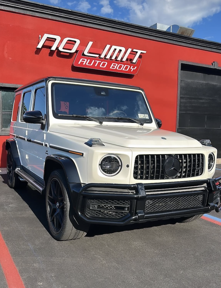 White Mercedes G-Wagon parked in front of No Limit Auto Body sign