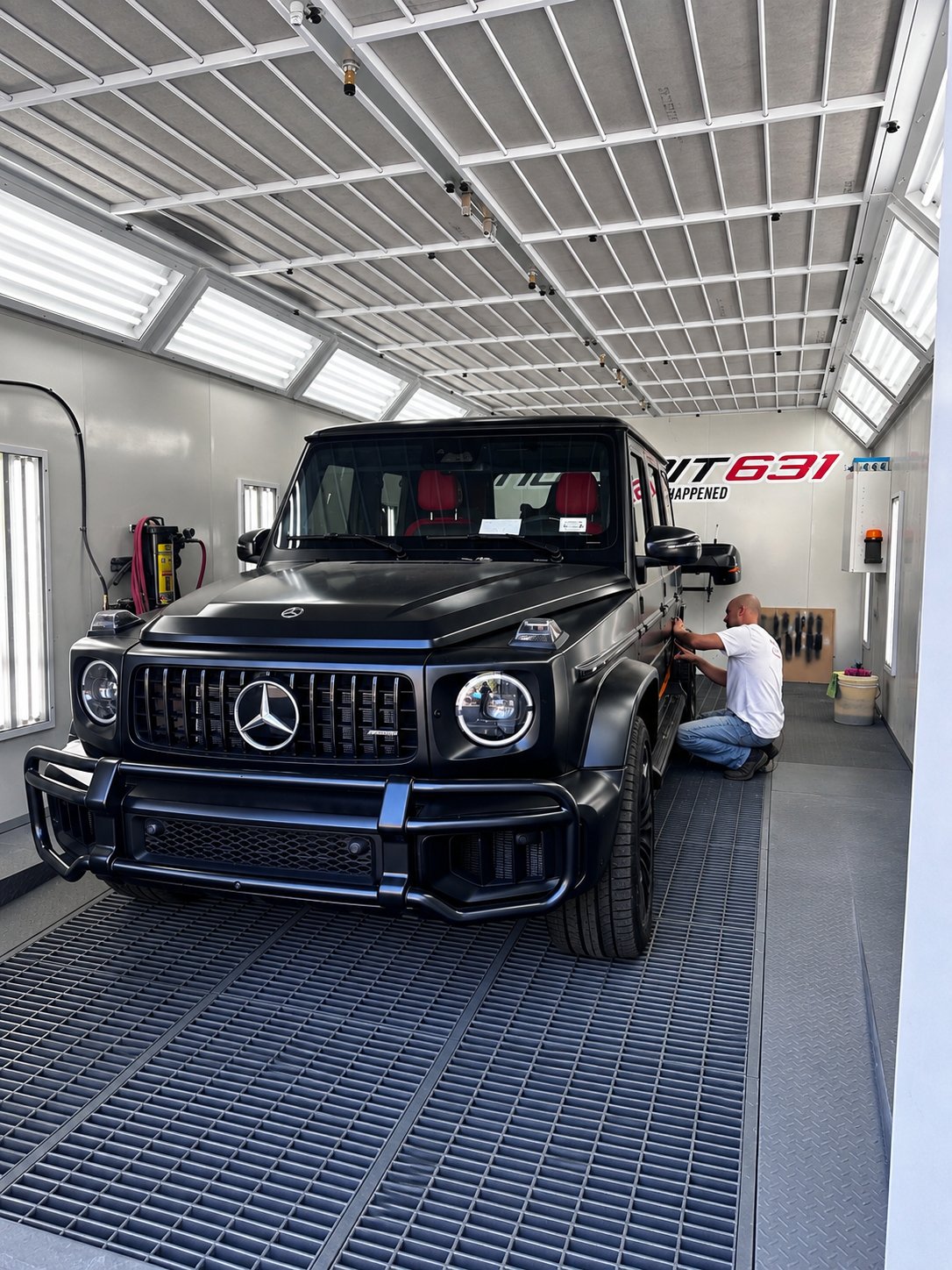 Technician working on a black Mercedes G-Wagon in the No Limit Auto Body paint booth