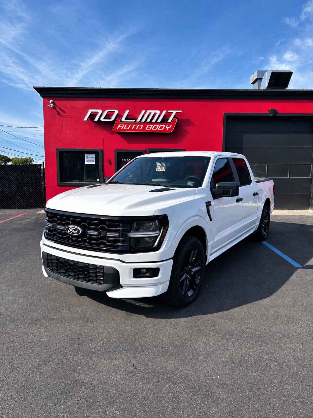 White Ford F-150 parked in front of the red No Limit Auto Body building