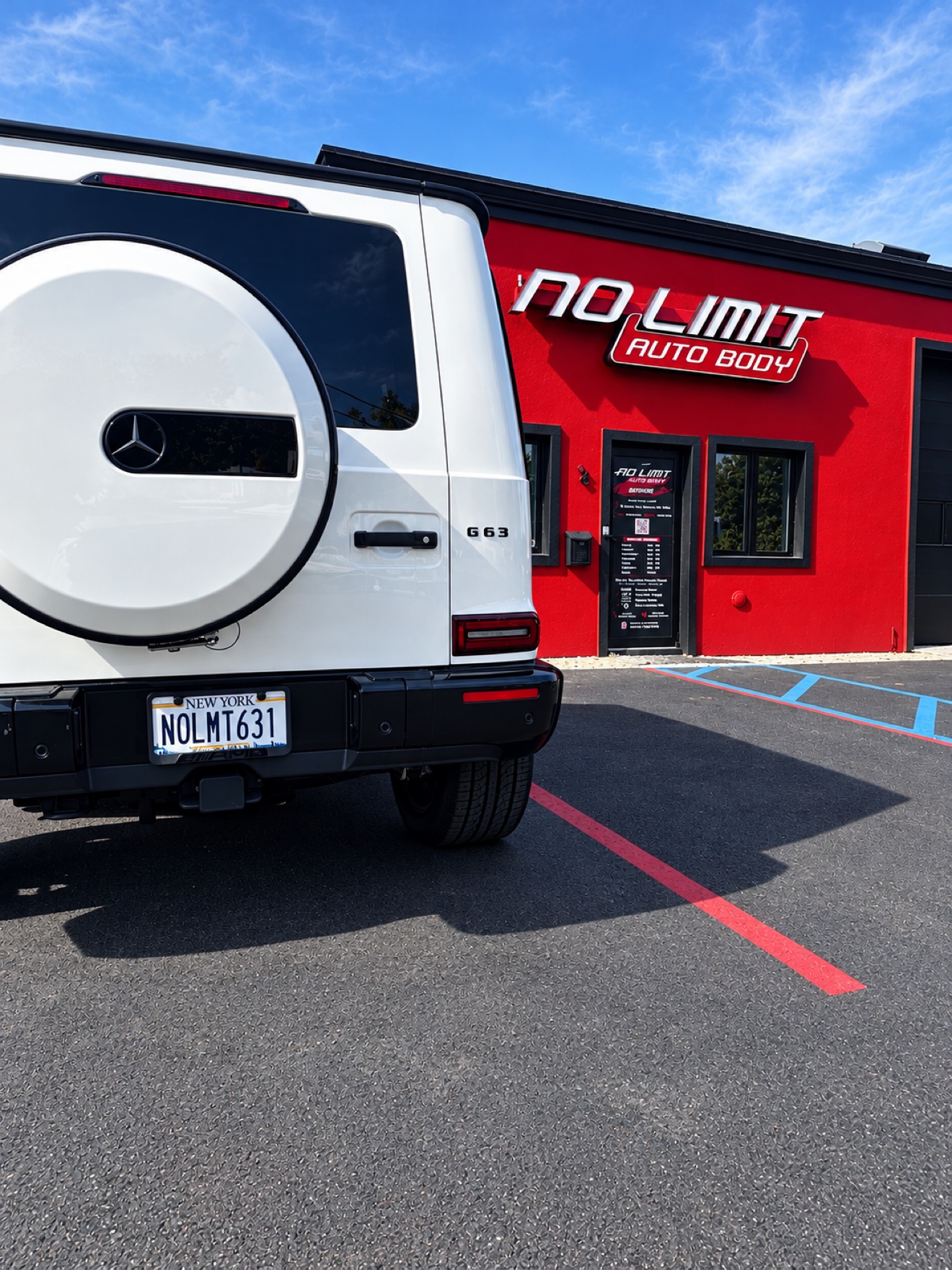 Rear view of a white Mercedes G63 with NOLMT631 plate in front of No Limit Auto Body