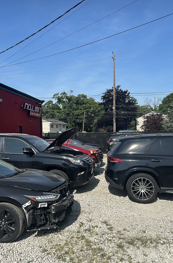 Customer vehicles in No Limit Auto Body gravel lot awaiting repair