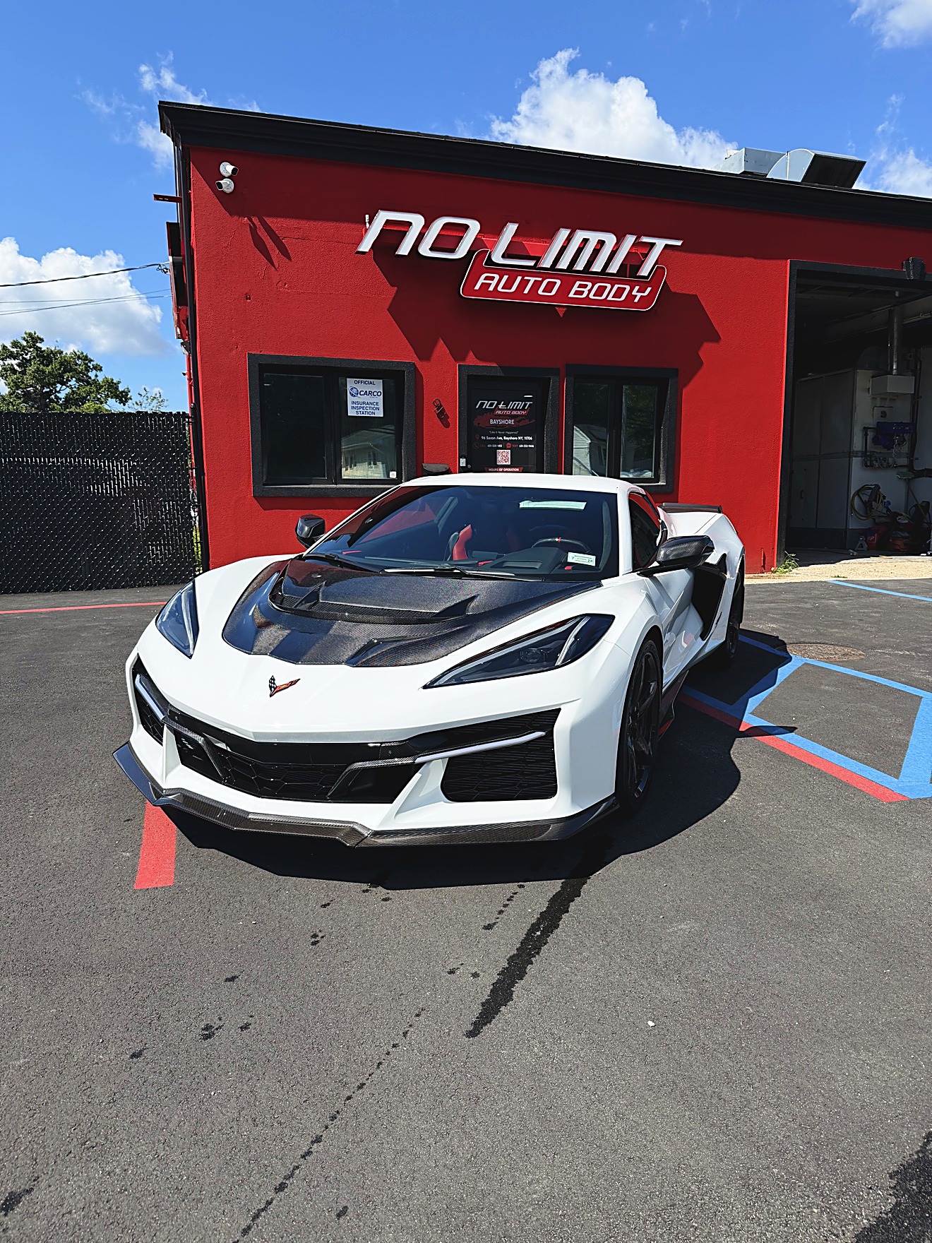 White Chevrolet Corvette C8 parked in front of the No Limit Auto Body building