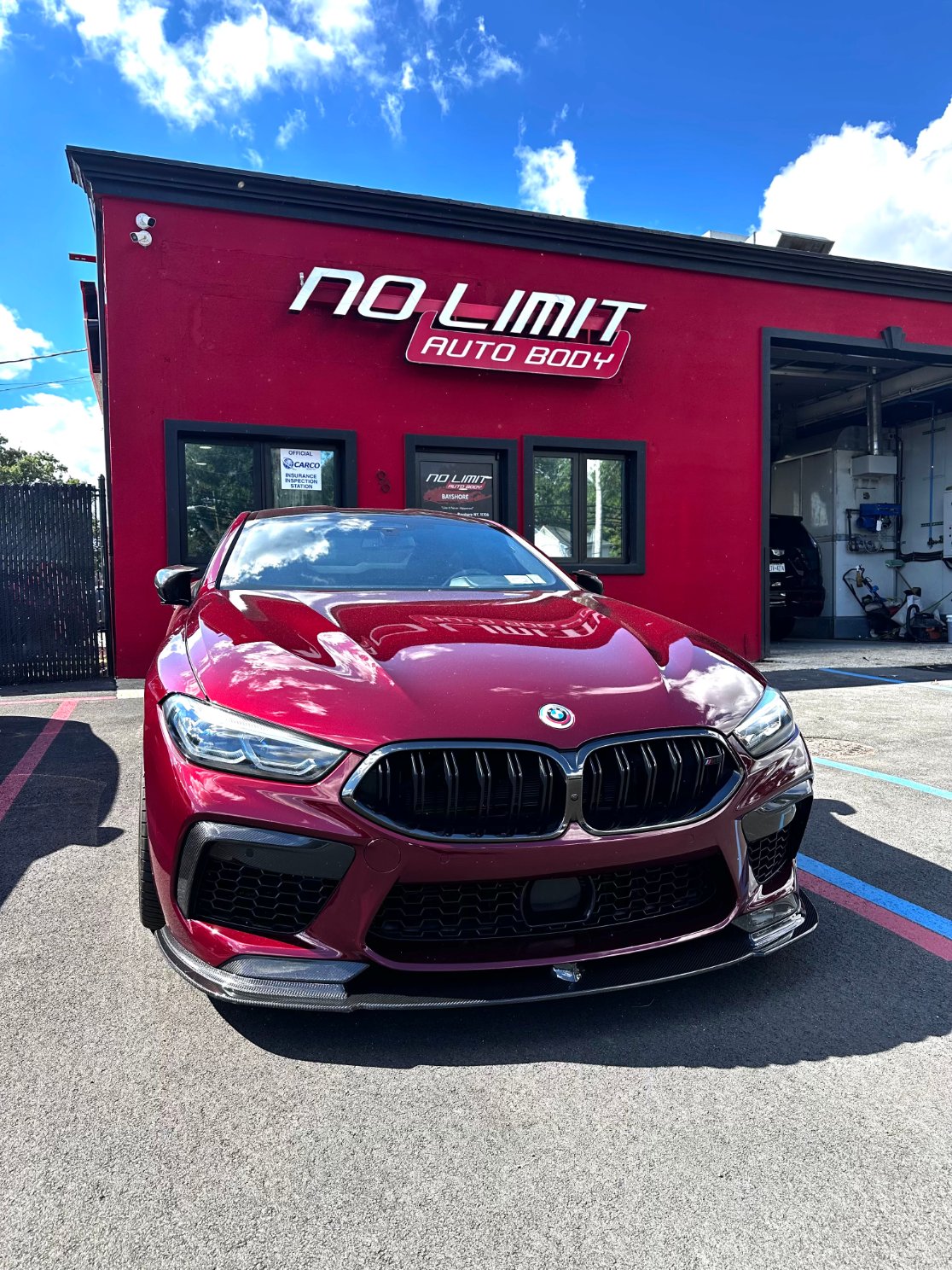 Red BMW M8 in front of the No Limit Auto Body shop
