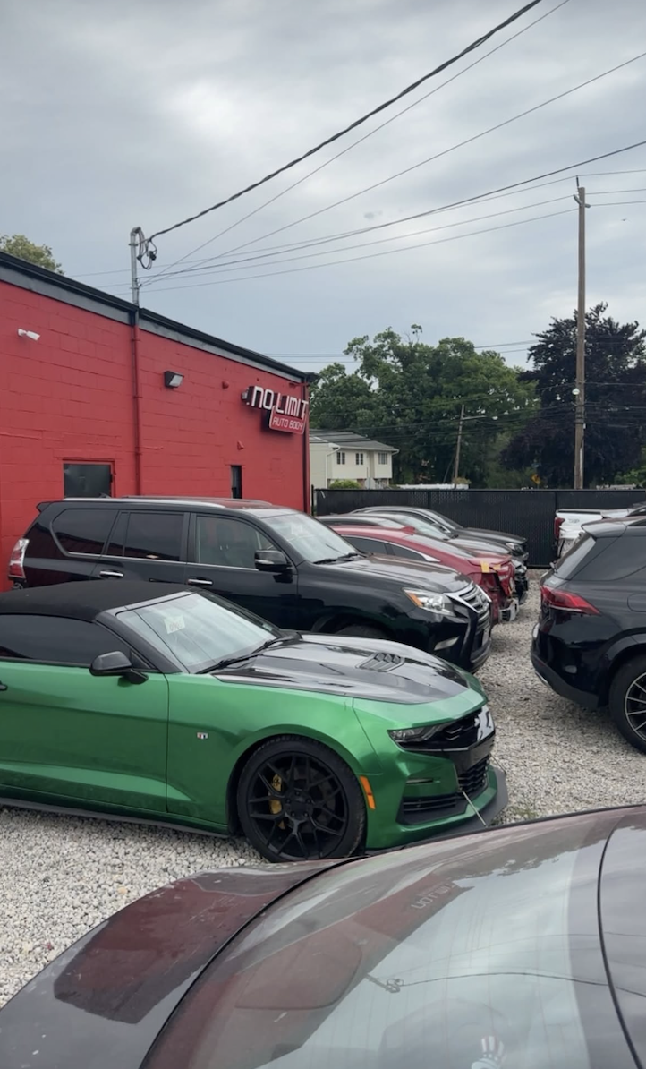 No Limit Auto Body lot with green Camaro and parked customer vehicles