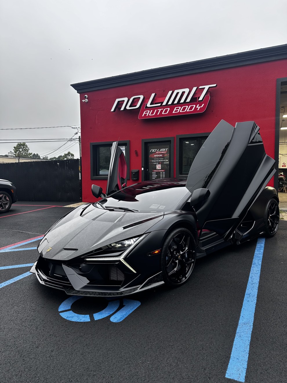Black Lamborghini Revuelto with scissor doors open in front of No Limit Auto Body