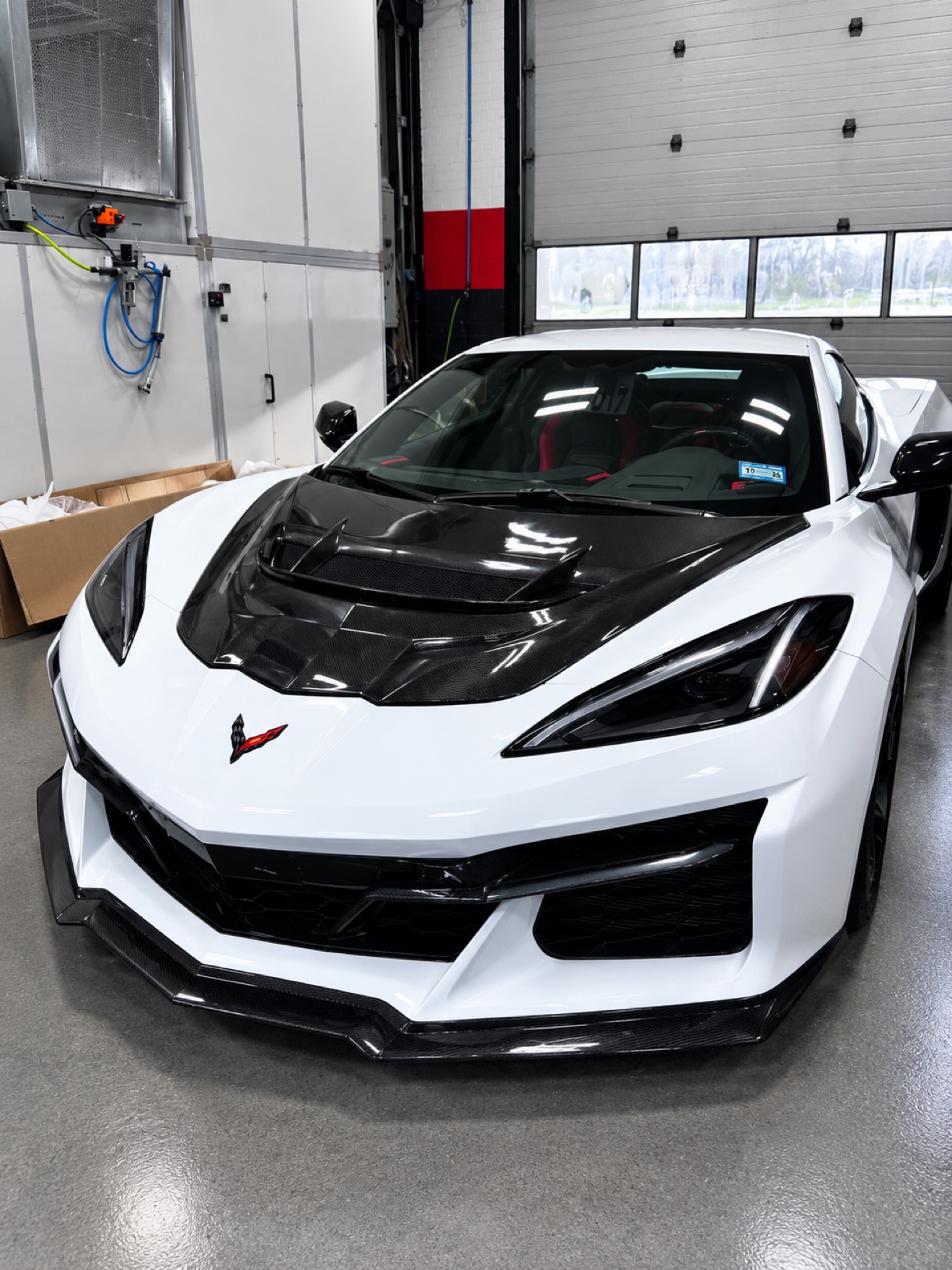 White Chevrolet Corvette C8 with carbon hood inside the No Limit Auto Body paint booth