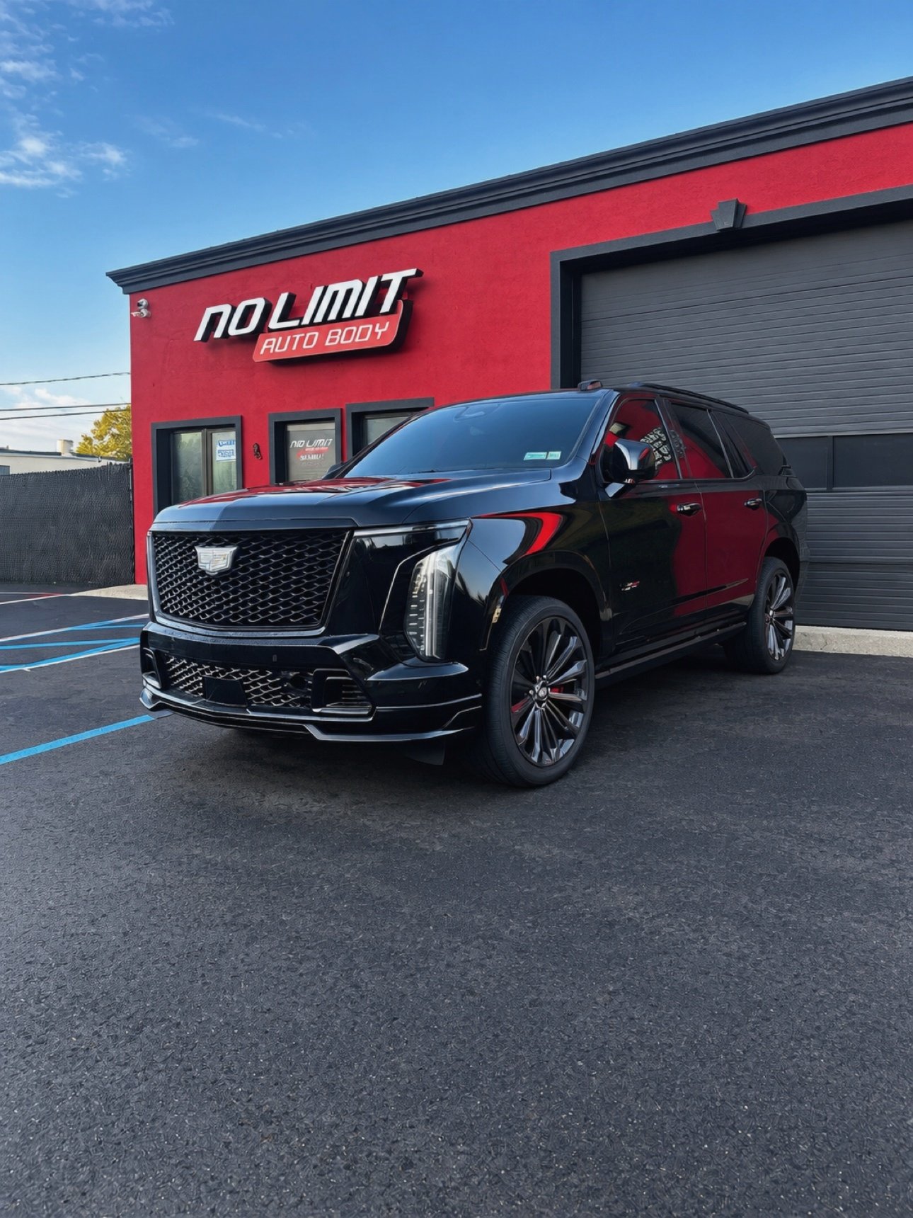 Black Cadillac Escalade in front of the No Limit Auto Body building